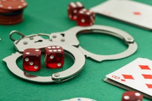 Dice, cards and prison handcuffs on a casino gaming table.