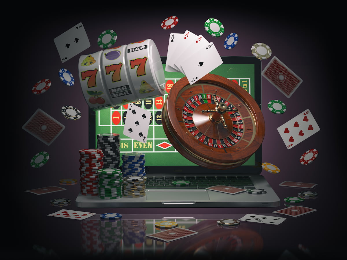 Roulette wheel, playing cards, gaming chips and slots exploding out of a laptop computer.