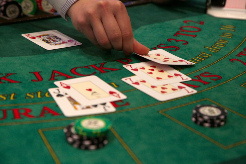 Dealer deals a third seven to a blackjack player to make a total of 21.