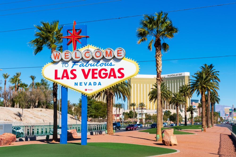 Welcome to Las Vegas sign next to palm trees on a sunny day.