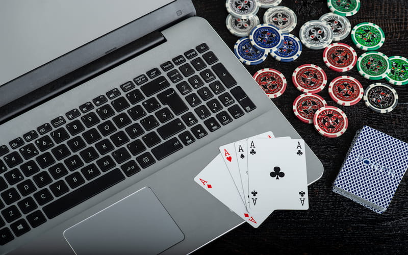 A laptop, some playing cards and casino chips