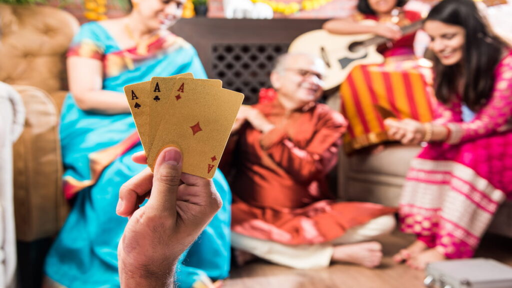 An over the shoulder look at the cards of a man playing Teen Patti with his family
