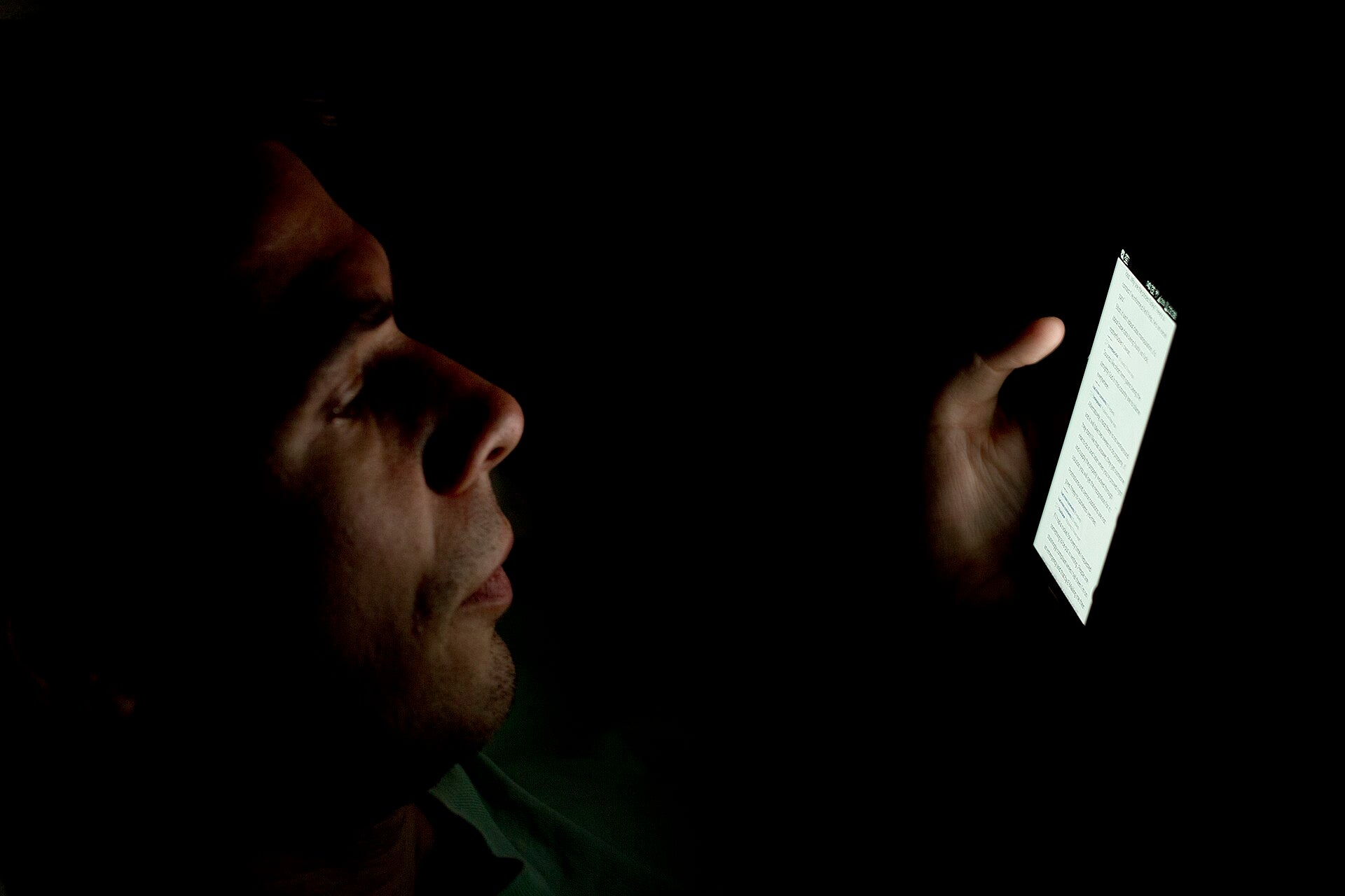 Ontario Gambling Helpline Calls Surge as Funding Lags Man checks smartphone in the dark, reflecting rising concern over online gambling access in Ontario