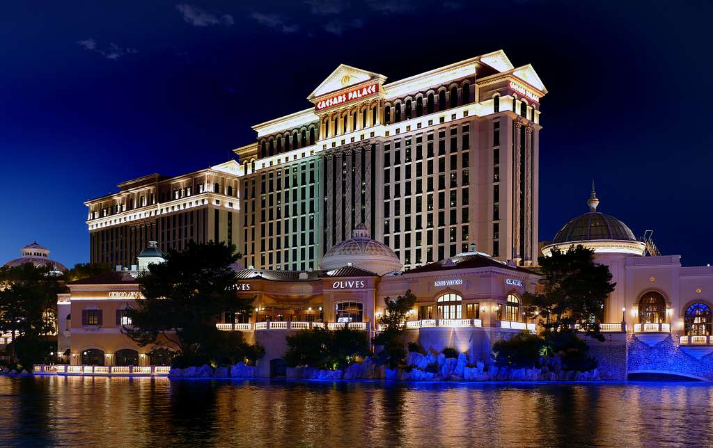 Trump Caesars Stock Sale Disclosed as Fertitta Deal Closes Caesars Palace hotel towers lit up at night behind the Bellagio lake on the Las Vegas Strip