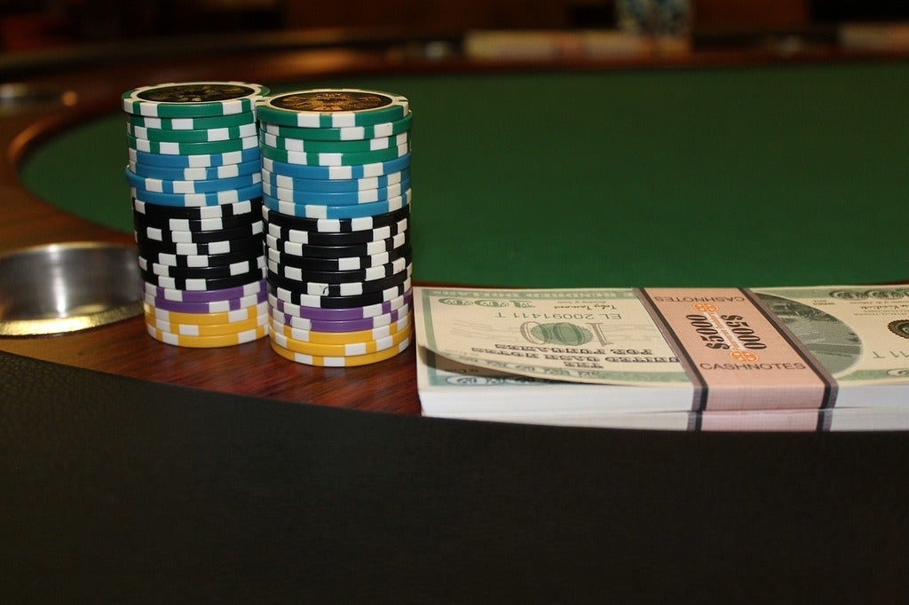Stacks of poker chips and cash bands on a green felt table, representing high-stakes WSOP Main Event poker