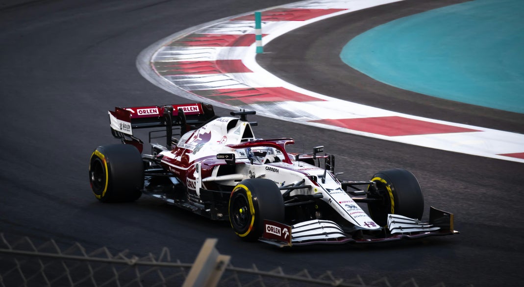 An Alfa Romeo F1 car with ORLEN sponsorship navigating a turn on a race track