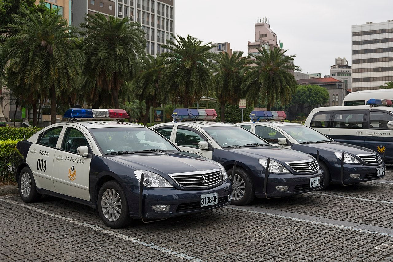 Taipei Police Vehicles | Law Enforcement Fleet in Urban Taiwan Row of Taipei police cars parked outside city headquarters with emergency lights and Chinese markings