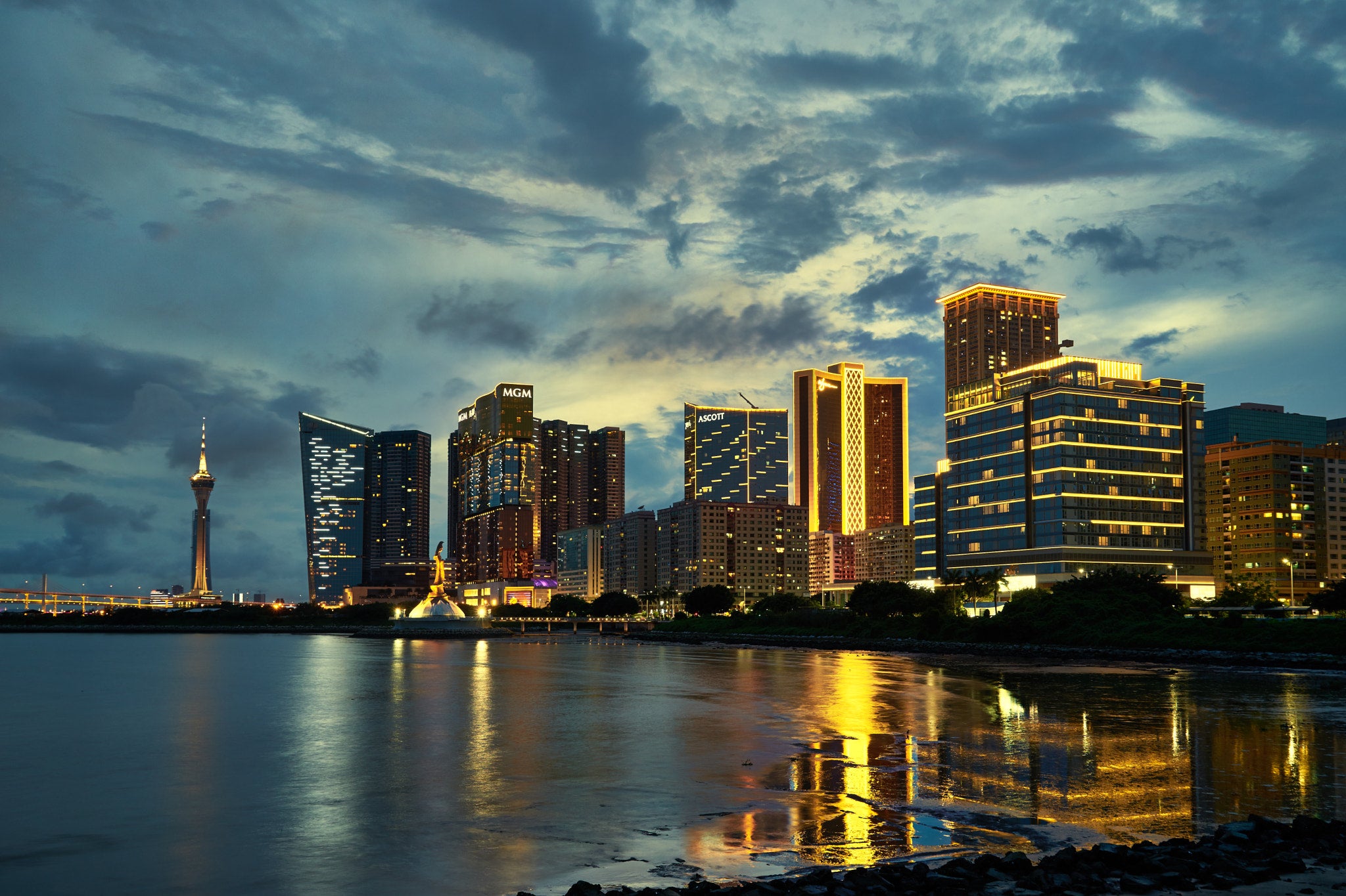 Macau GGR Dips in June as FIFA World Cup Steals Gamblers Macau skyline at dusk with MGM casino and Macau Tower reflected in the waterfront