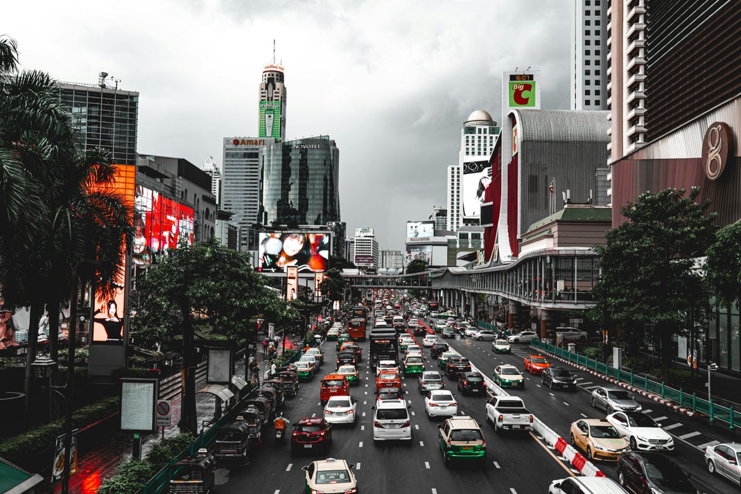 Heavy traffic on a busy Bangkok city street with skyscrapers and billboards in the background