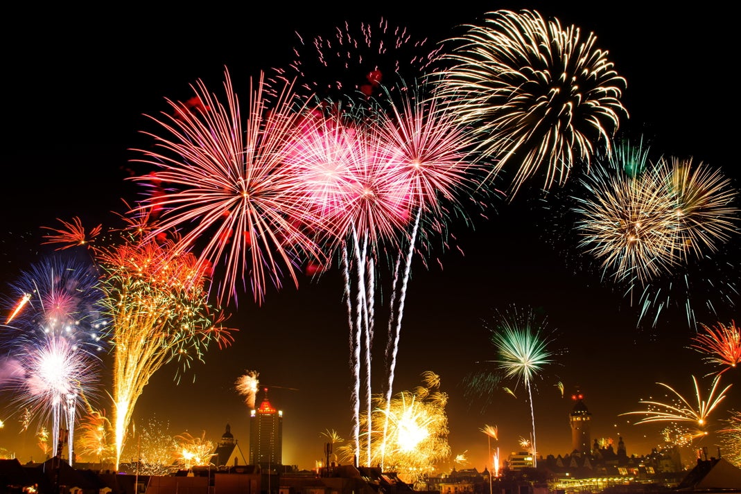 Colorful fireworks bursting over a city skyline at night during a large outdoor celebration