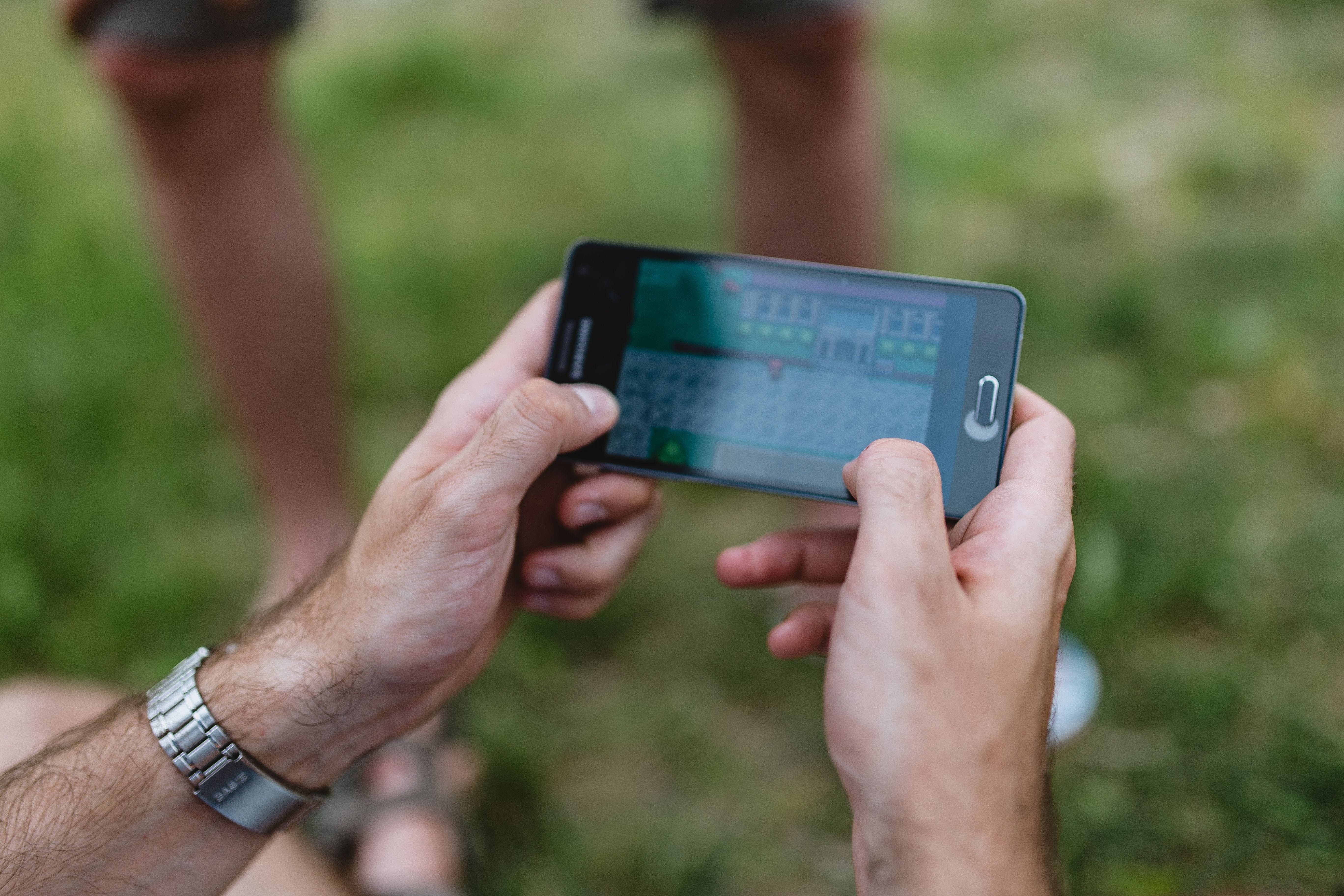Ontario iGaming Wagers Hit Record CA$9.88B in July 2026 Close-up of a man holding a smartphone outdoors while playing a retro-style video game, symbolizing mobile gaming and digital entertainment trends