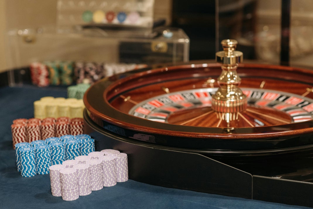 A roulette wheel and stacked casino chips on a blue gaming table