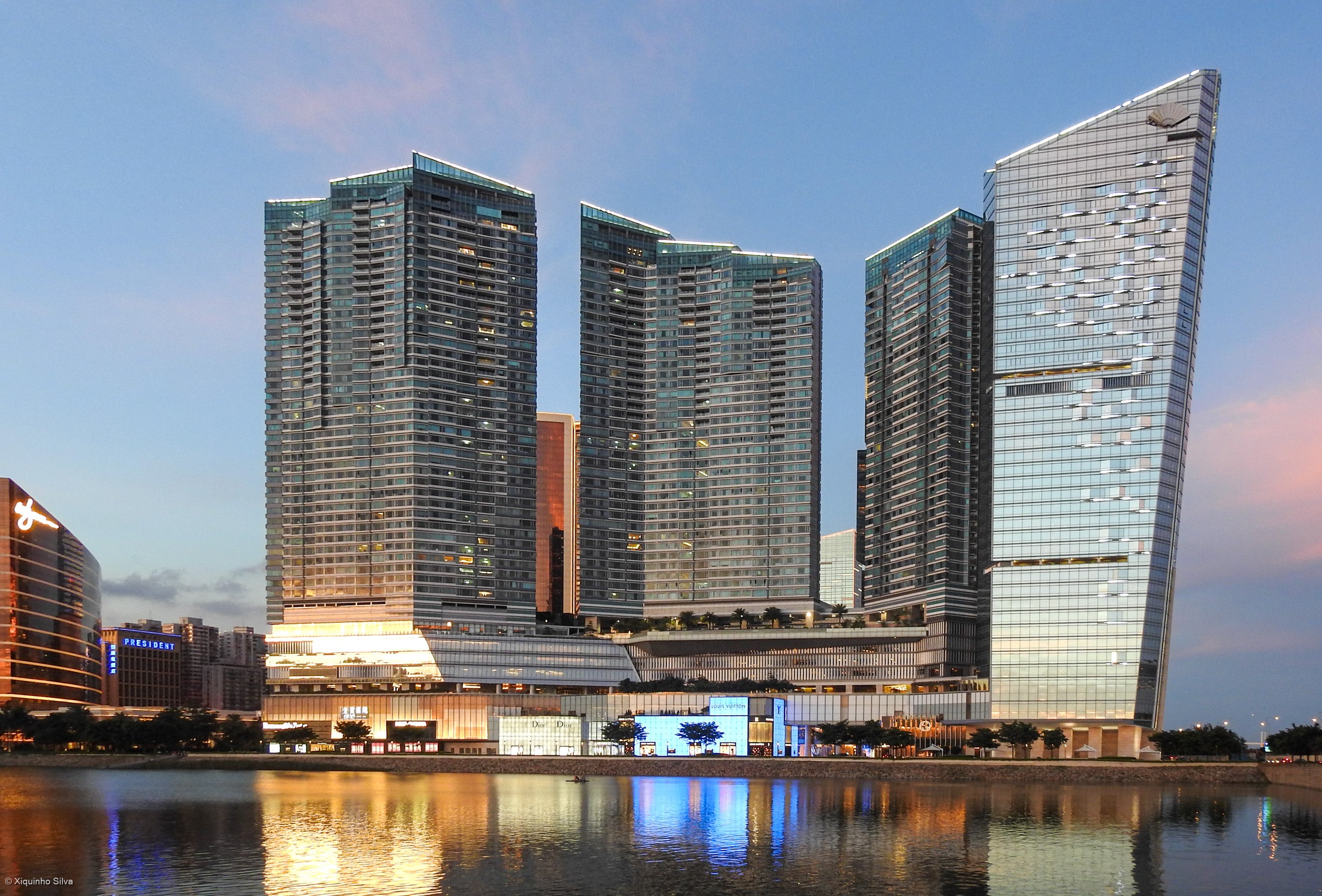 Macau Gaming Tax Revenue Hits MOP$51.2 Billion in H1 2026 Macau skyline at dusk showing luxury casino resort towers reflected in Nam Van Lake, with the President Hotel visible in the background