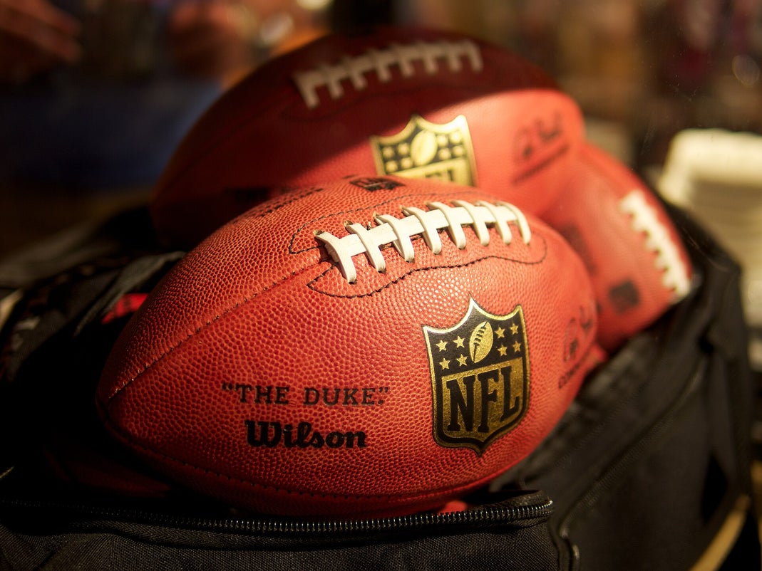 NFL Wilson Duke footballs stacked on top of a bag