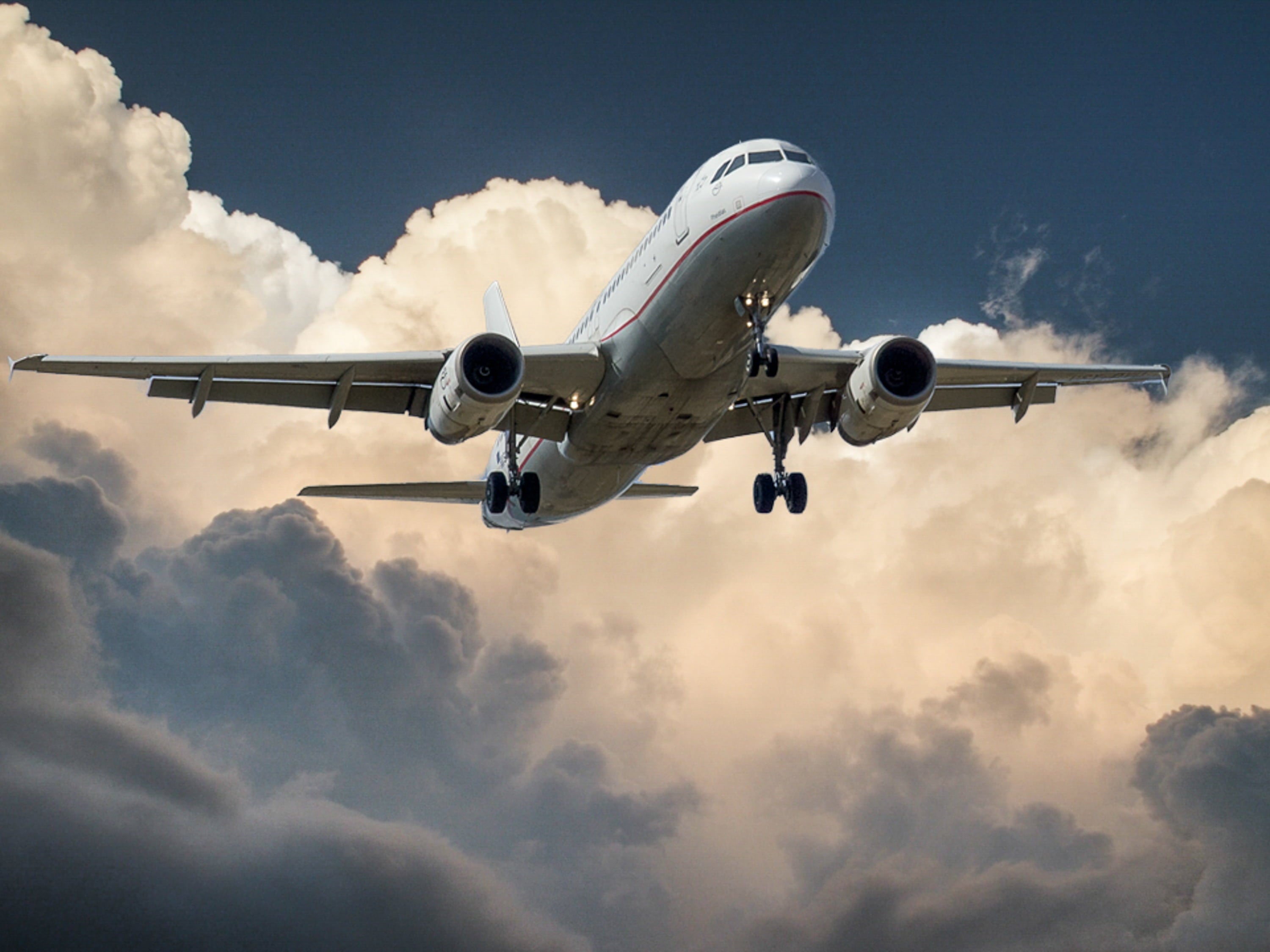 Commercial airplane descending through dramatic clouds with landing gear extended