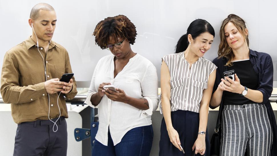 Multiethnicity colleagues looking at their mobile phones during the break time in the office