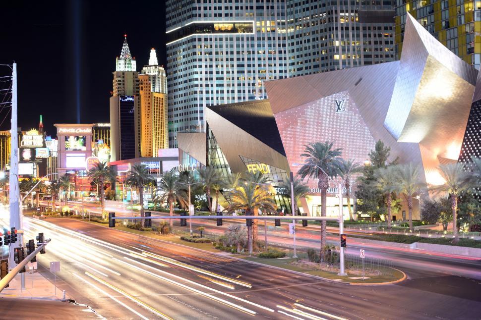 Night view of the Las Vegas Strip with luxury storefronts, neon lights, and iconic hotels glowing against the city skyline