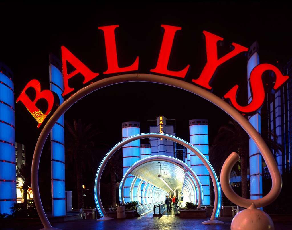 Bally's Completes Sam's Town Shreveport Acquisition Bally's illuminated red sign and glowing archway entrance at night in Las Vegas