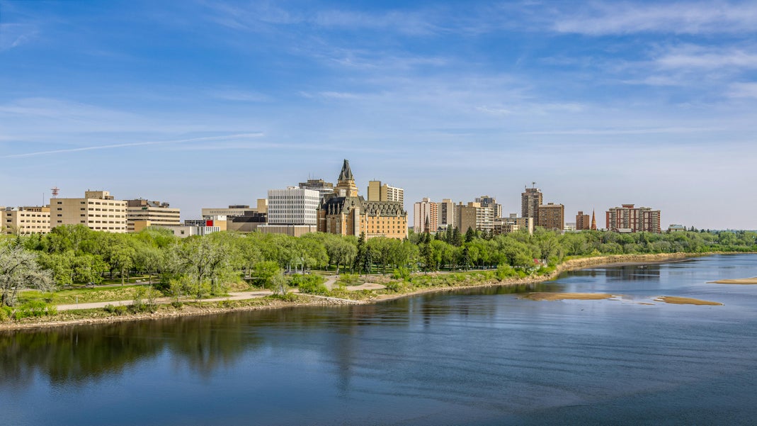 Downtown Saskatoon skyline with Delta Bessborough hotel and riverbank park along the South Saskatchewan River in spring