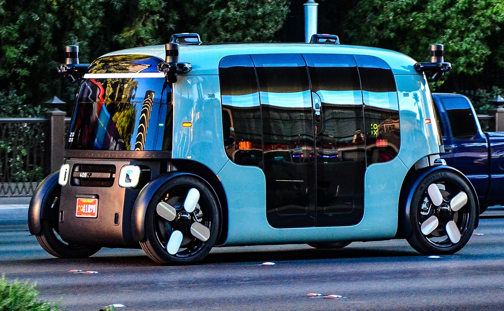 Resorts World Las Vegas Zoox Robotaxi Partnership 2025 Zoox robotaxi, a driverless four-passenger vehicle with no steering wheel, driving on a Las Vegas street