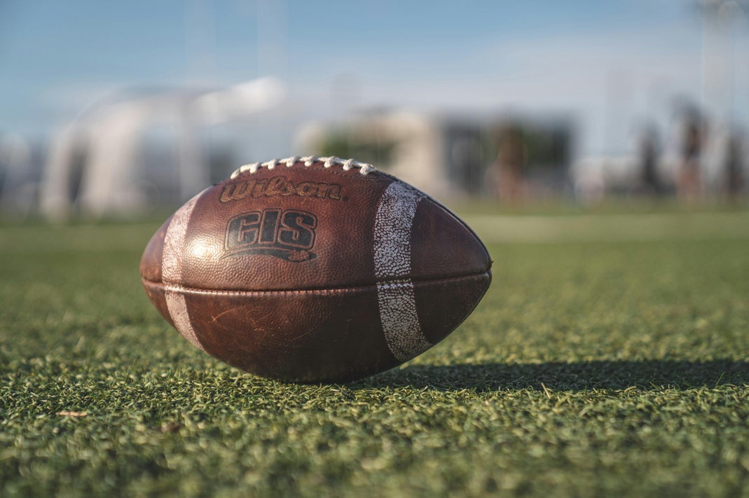 Close-up of a Wilson pigskin American football resting on green grass on an outdoor field