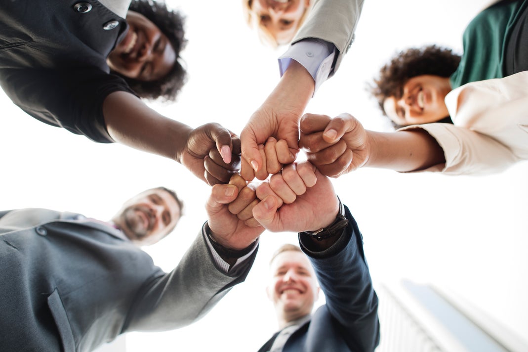 A Group of People Fist Bumping in Collaboration