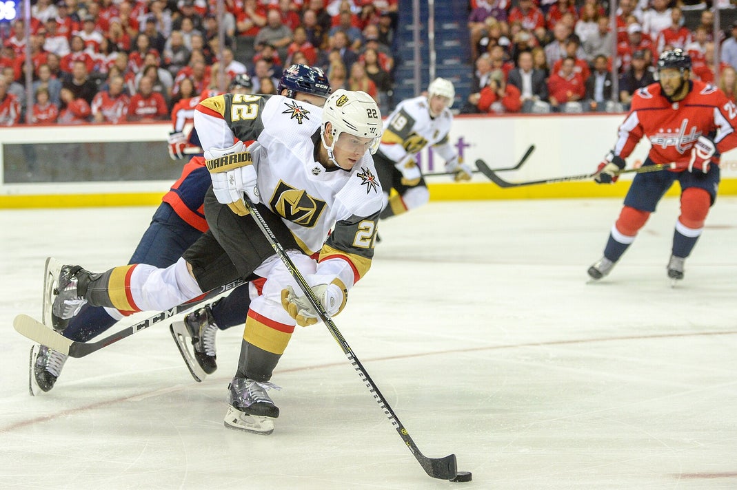 A Vegas Golden Knights player wearing number 22 controls the puck while being pressured by a Washington Capitals defender during an NHL game