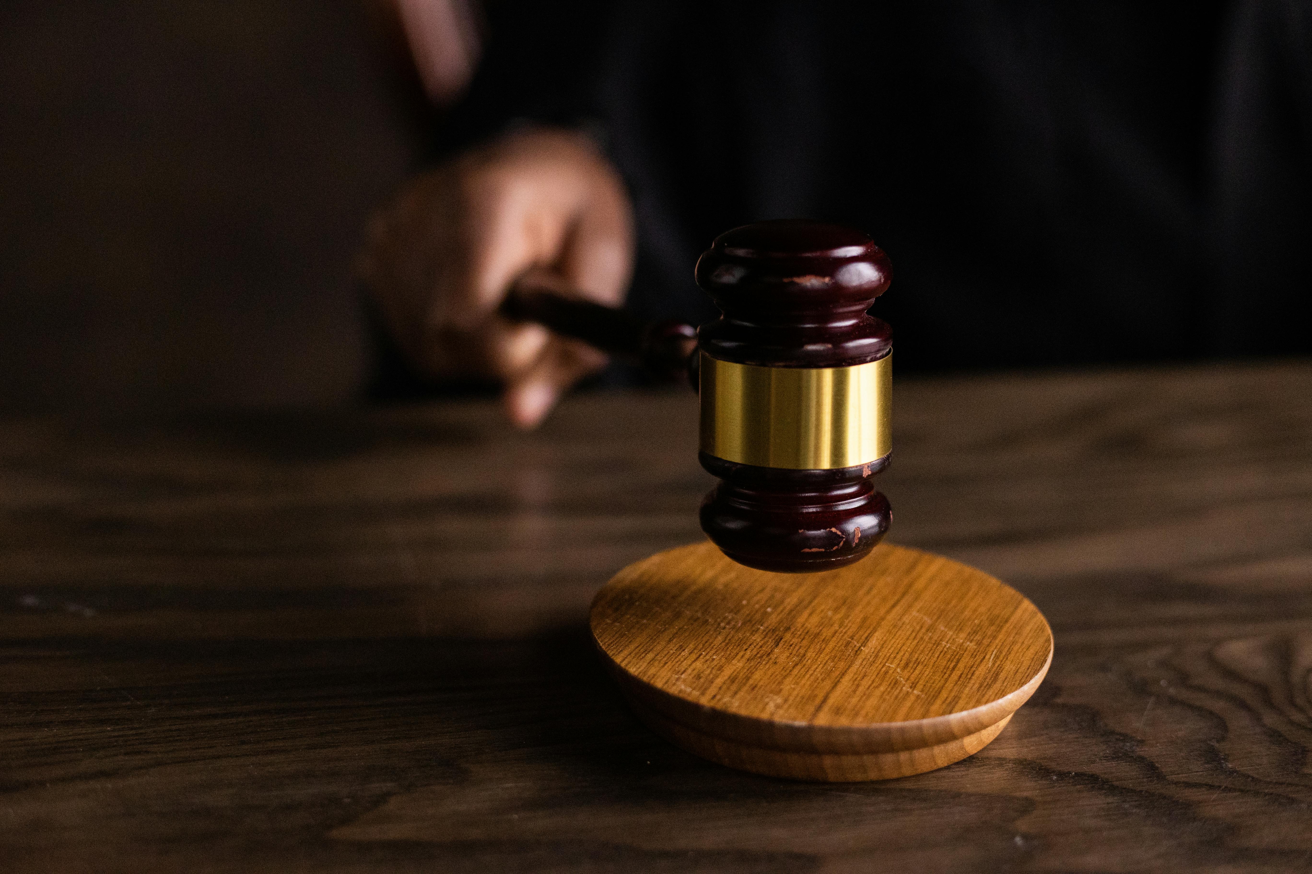 Close-up of a judge's gavel hitting a wooden sound block, symbolizing justice and legal authority in a courtroom