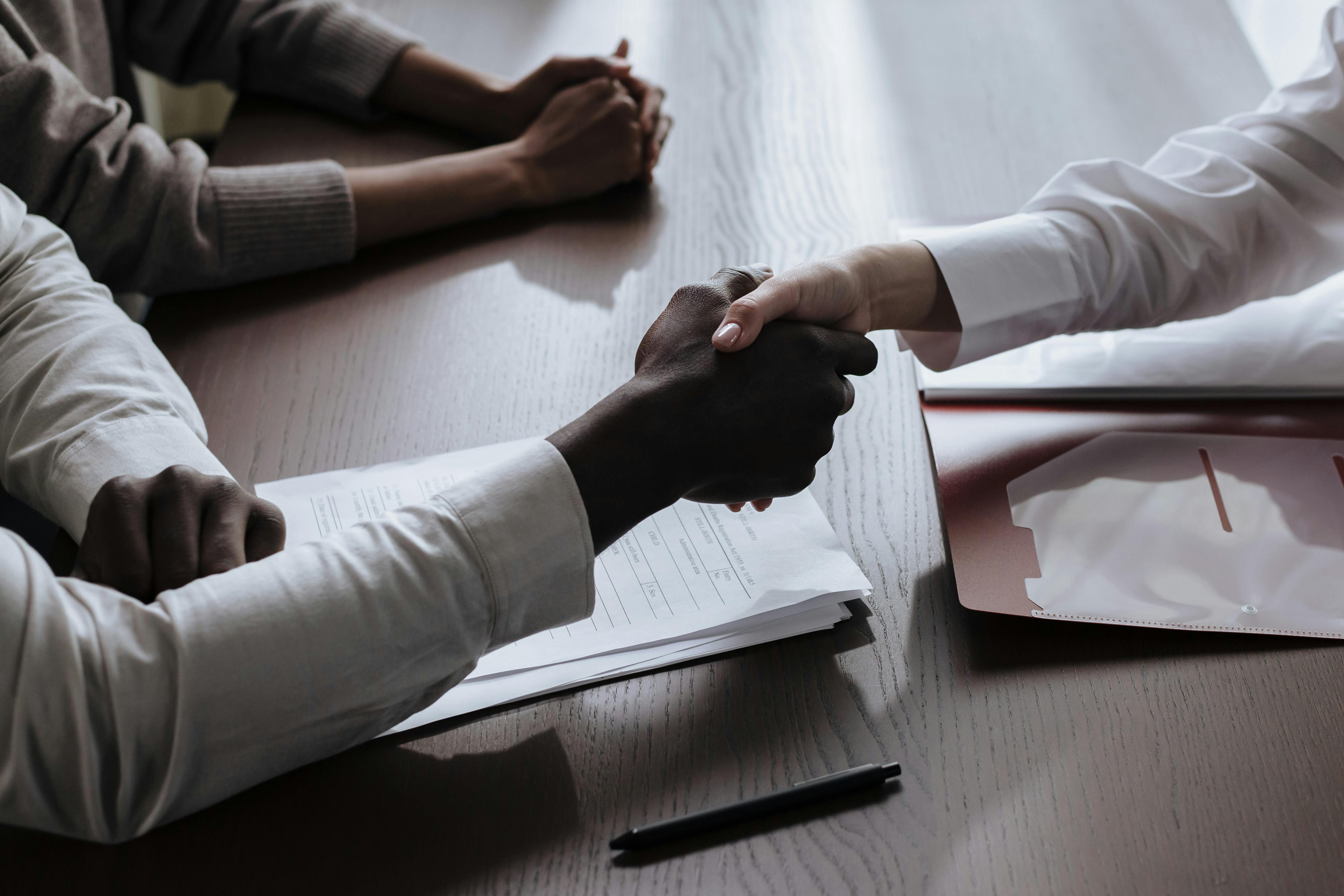 Business handshake between two people during a partnership meeting at an office desk