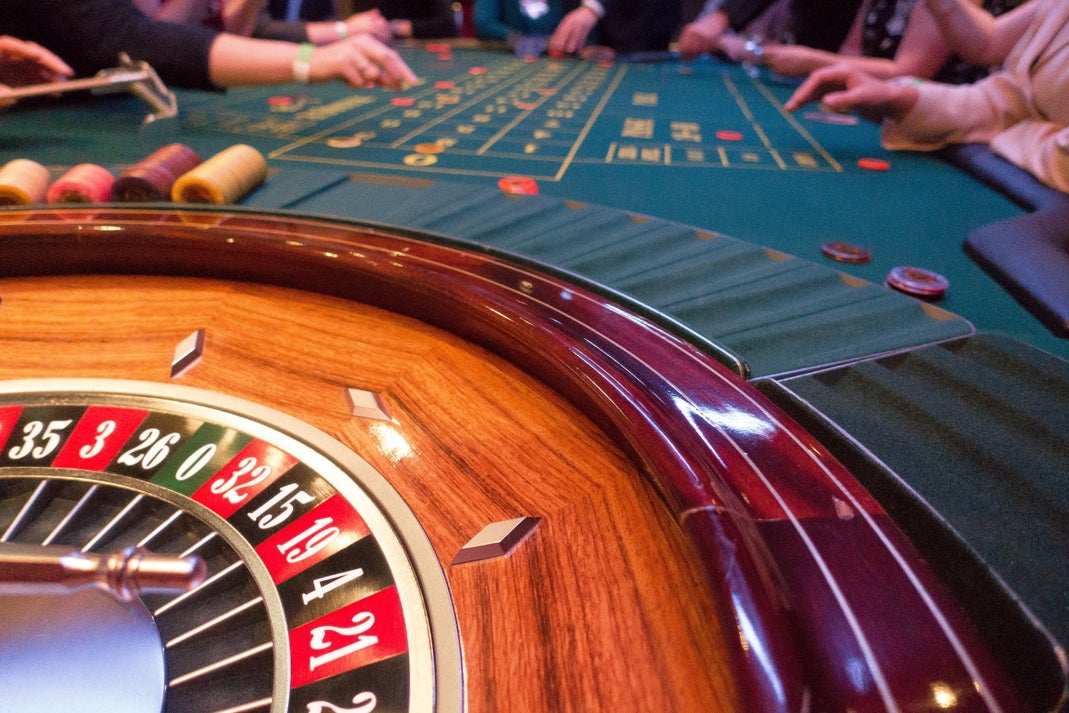Close-up of a casino roulette wheel and betting table with players placing chips