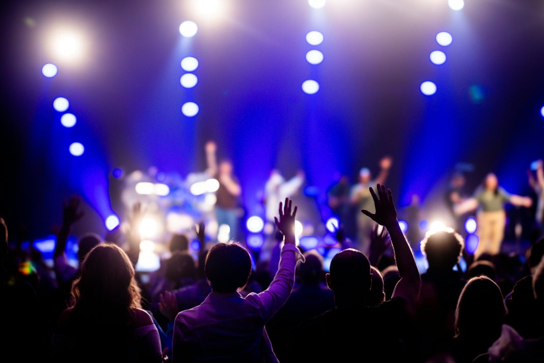 Crowd with raised hands enjoying a live music concert under bright stage lights