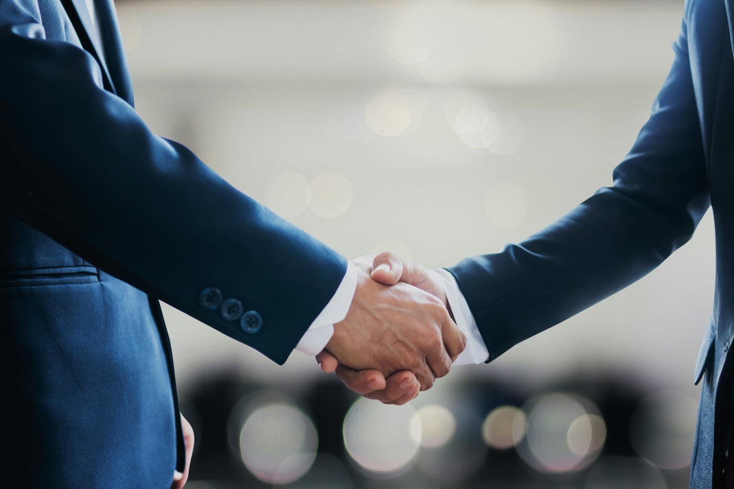 Business Handshake Symbolizing Corporate Deal and Partnership Two business professionals in dark suits shaking hands to symbolize a successful agreement or acquisition