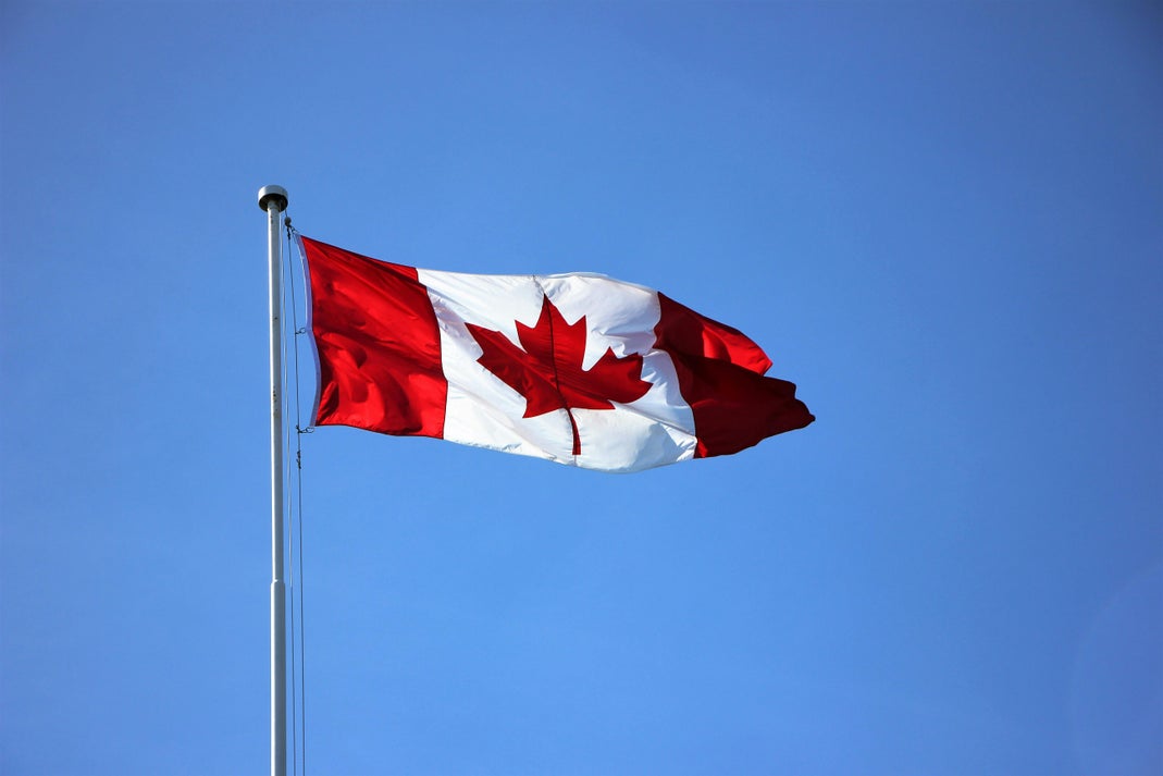 Canadian flag waving against a blue sky