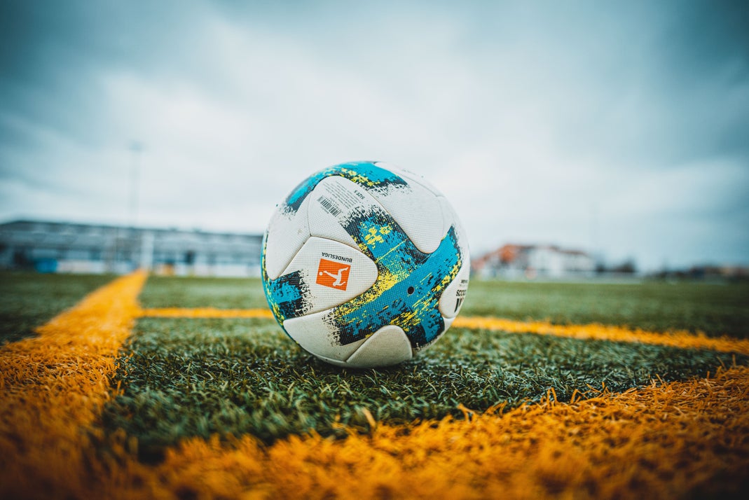 Close-up of a Bundesliga football resting on an artificial turf soccer field under cloudy skies