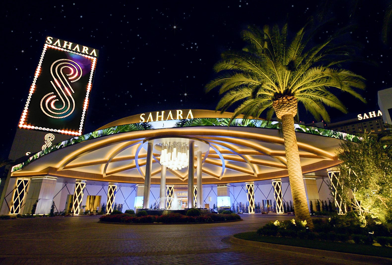 SAHARA Las Vegas Crypto: Fund Casino Play With Bitcoin Illuminated porte cochère entrance with chandelier and SAHARA signs at SAHARA Las Vegas at night, framed by a palm tree