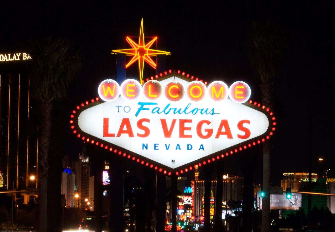 The Welcome to Fabulous Las Vegas Nevada sign lit up at night with the Strip in the background