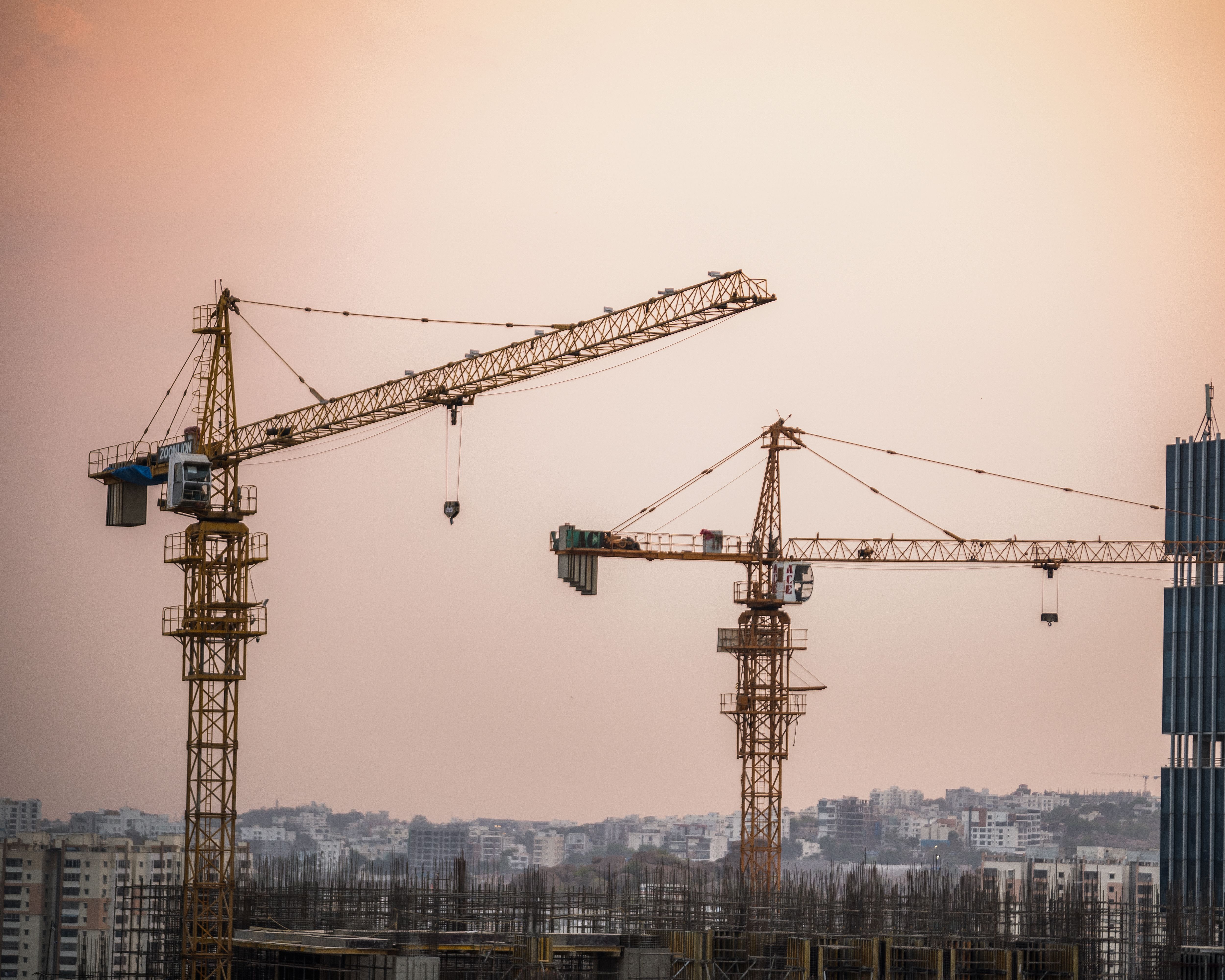 Skyline view of an urban construction site with prominent tower cranes at dusk