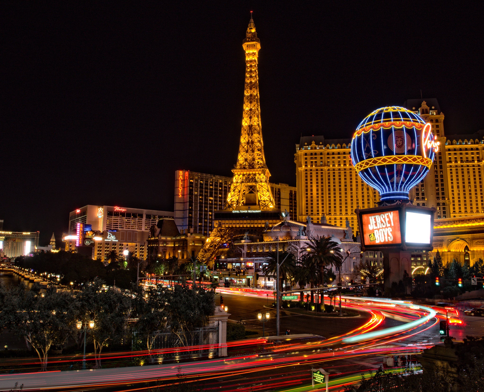 Night view of the Las Vegas Strip with light trails from traffic and Paris Las Vegas in the background