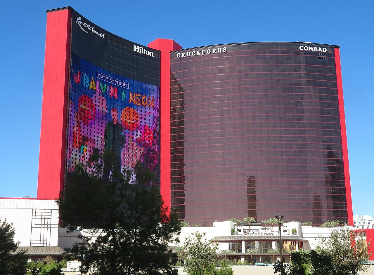 Exterior view of Resorts World Las Vegas with red hotel towers and large LED display on the building facade