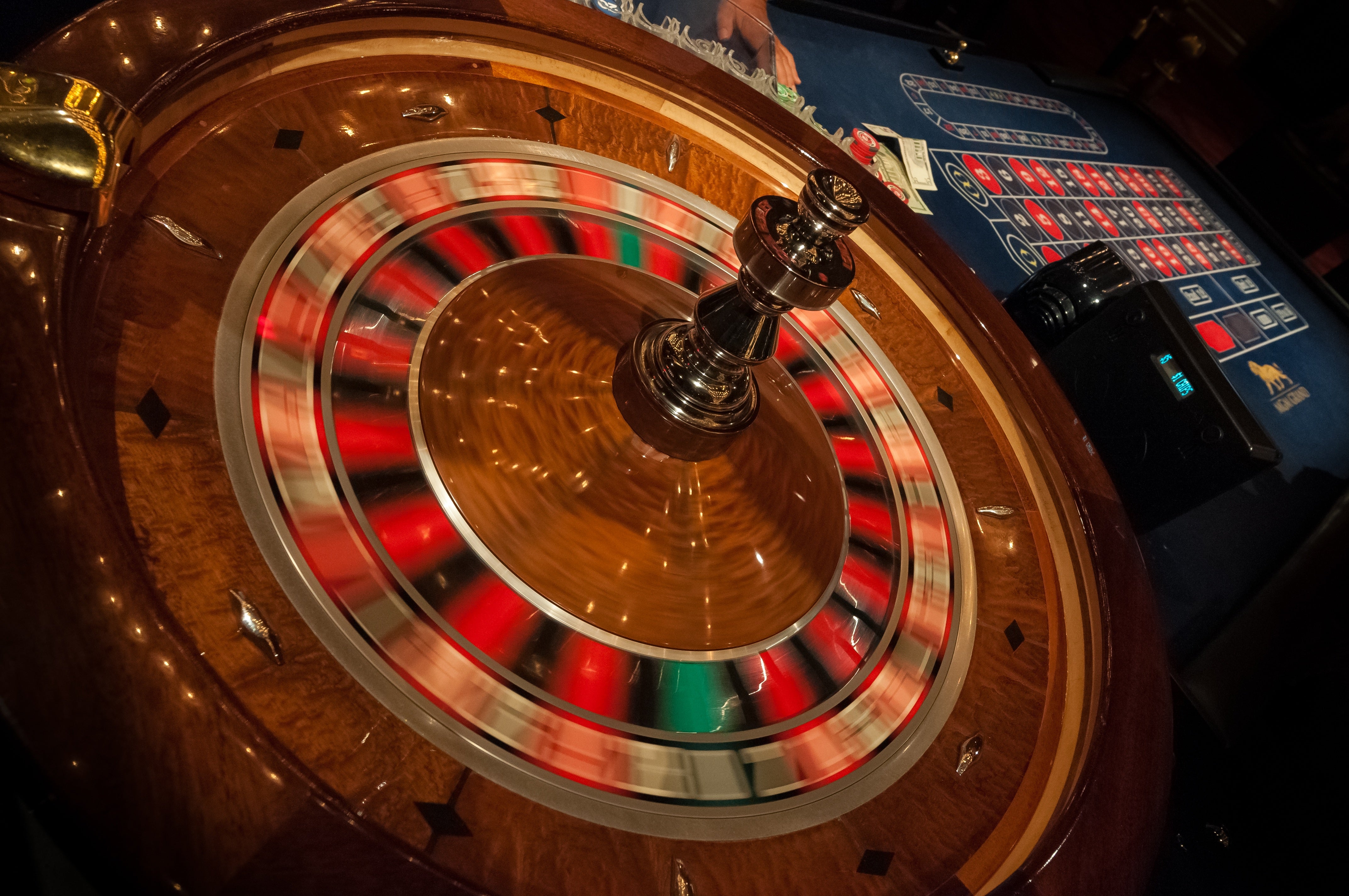Ontario Online Casino Revenue Hits Record $326.4M in May Blurred roulette wheel spinning in motion at a casino table, with betting chips and cash visible on the felt layout
