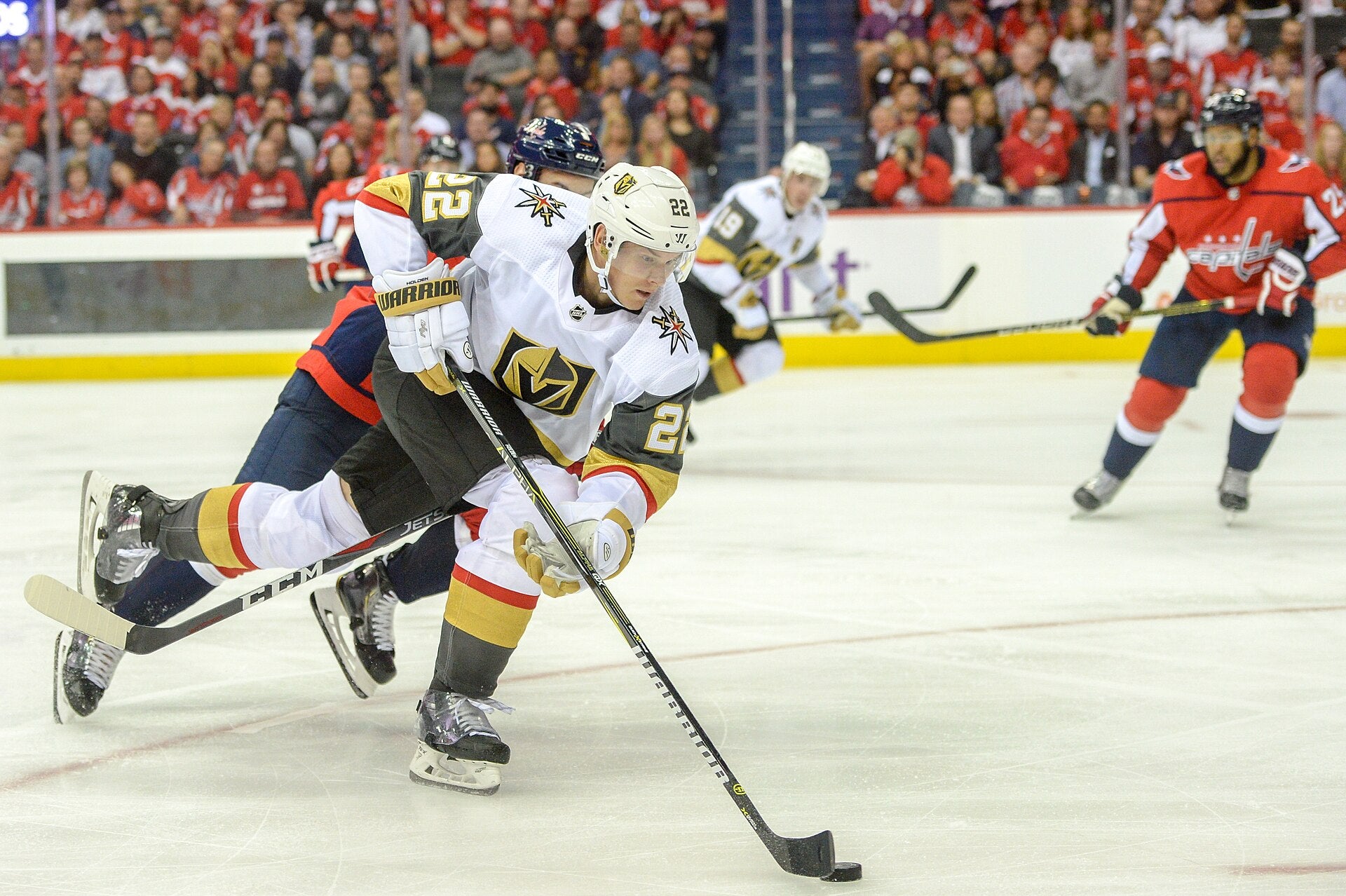 A Vegas Golden Knights player wearing number 22 controls the puck while being pressured by a Washington Capitals defender during an NHL game