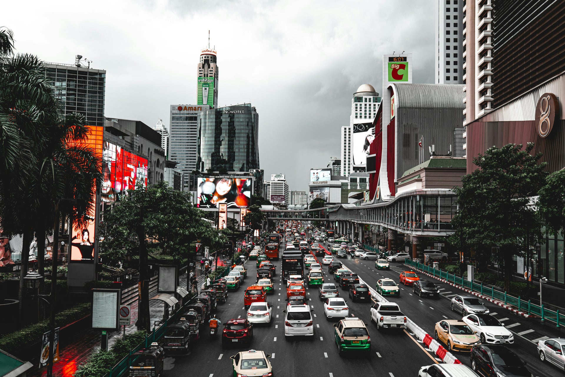 Heavy traffic on a busy Bangkok city street with skyscrapers and billboards in the background