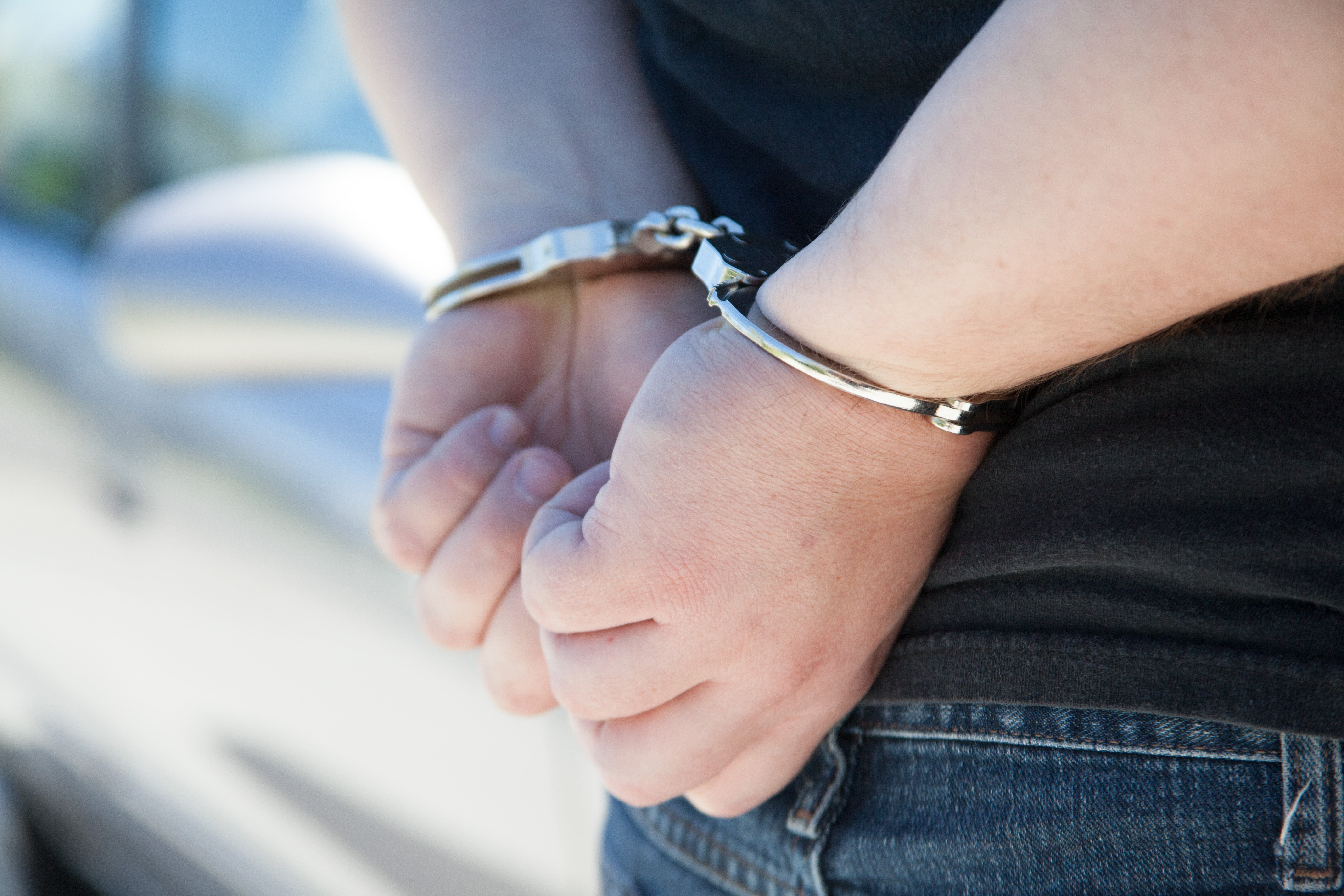 Close-up of handcuffed wrists behind a person's back, representing the arrest of a Las Vegas woman charged with bigamy and fraud
