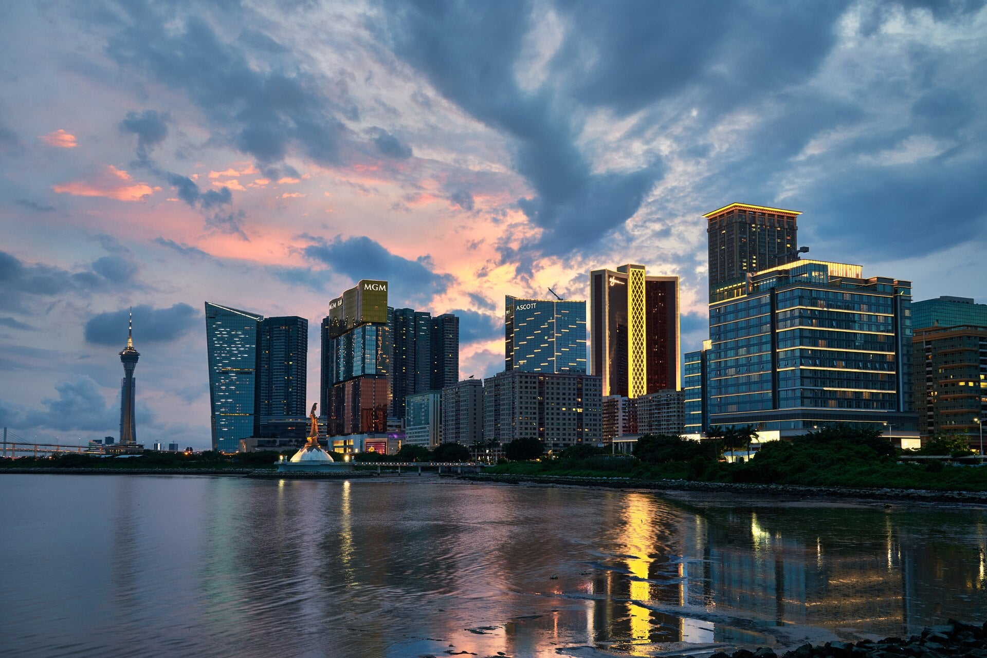 Macau GGR Hits $2.8B in May 2026, Beating All Forecasts Macau skyline at sunset showing MGM, Ascott, and Wynn towers reflected in the waterfront