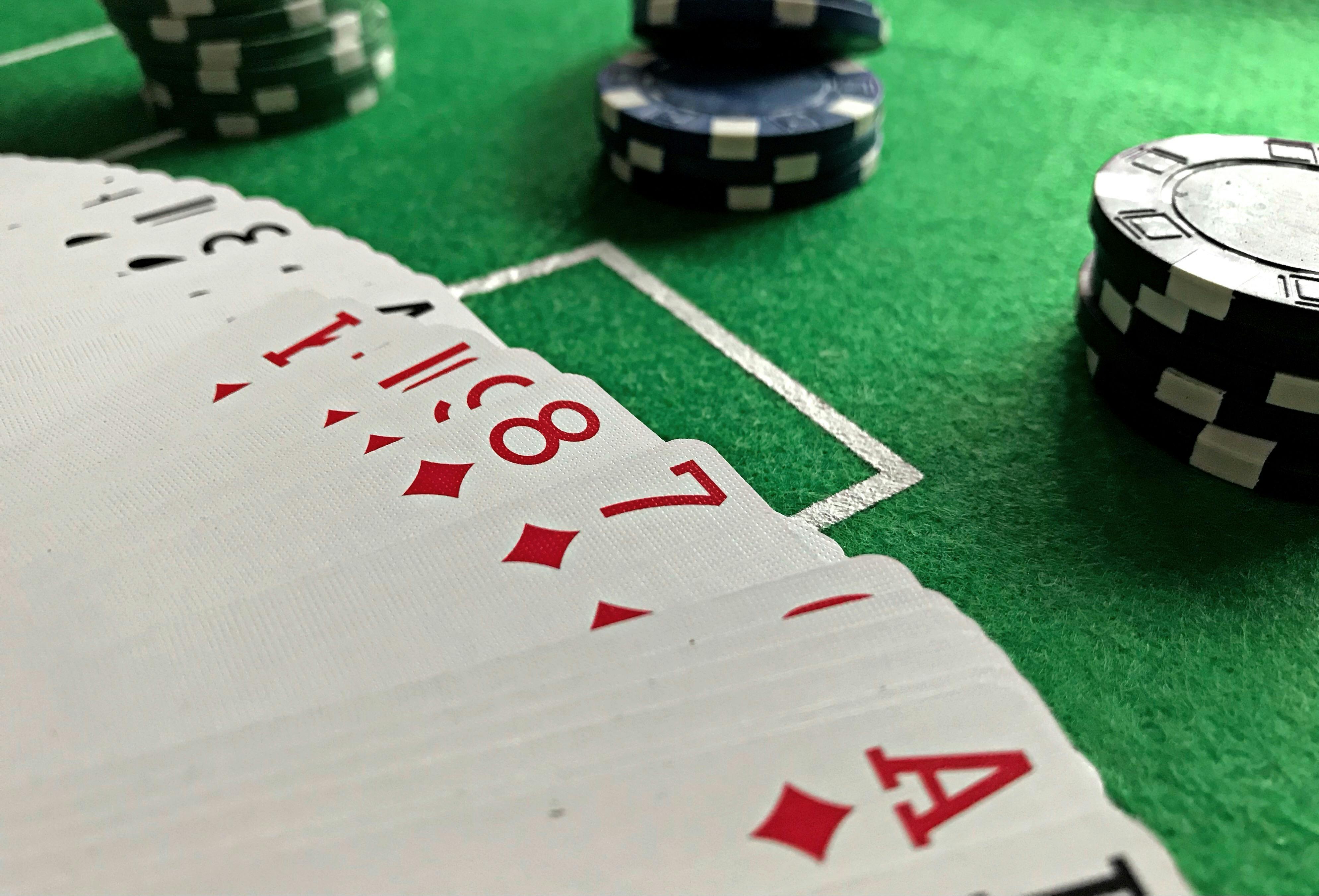  Close-up of playing cards and poker chips on a green casino table
