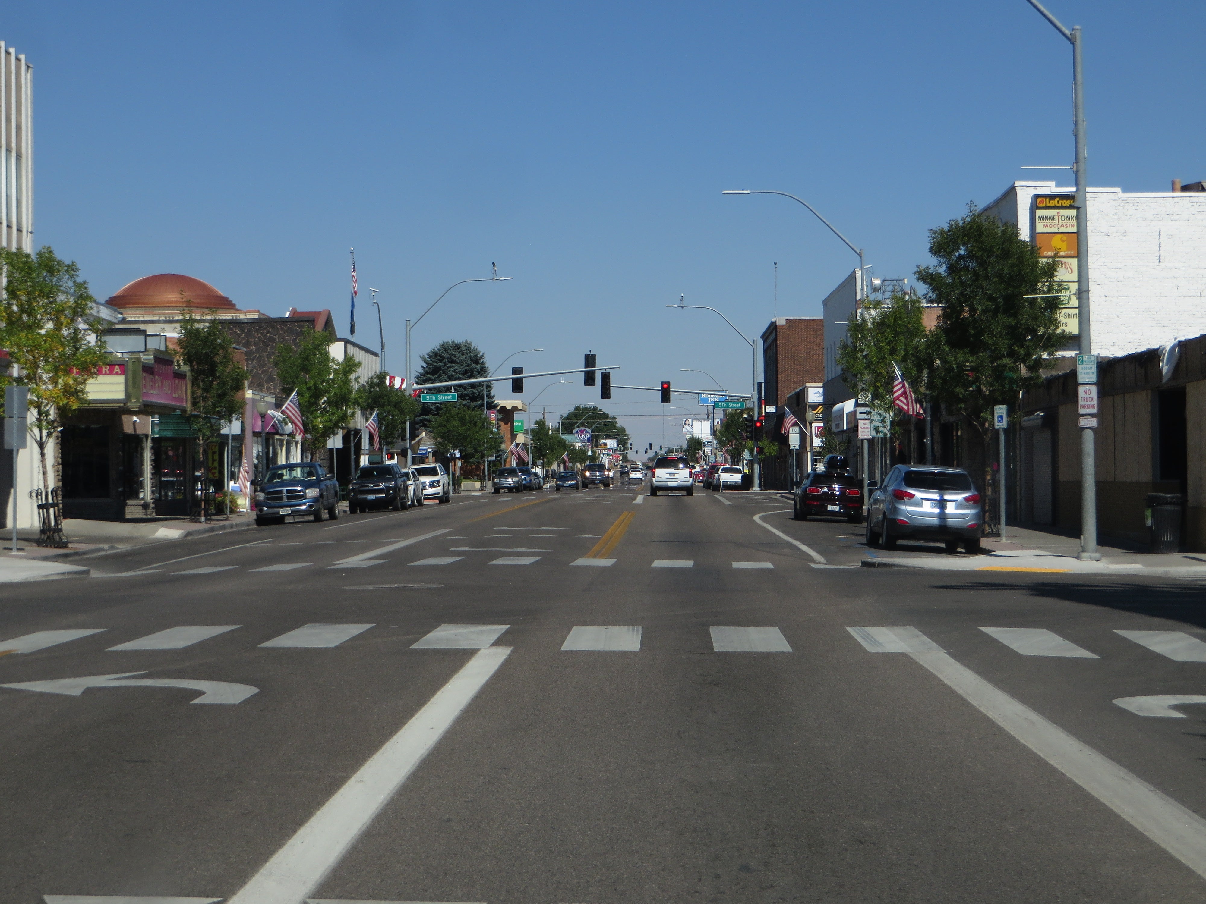 Elko Casino Closures: 239 Jobs Tied to Persson Buyback Idaho Street in downtown Elko, Nevada, lined with shops, parked cars and American flags under a clear blue sky