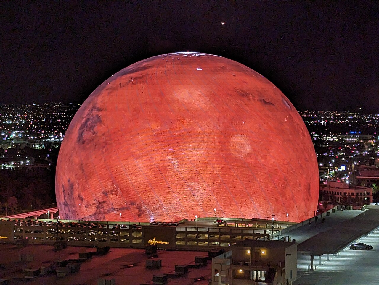 The Sphere in Las Vegas illuminated at night with a Mars-themed LED display, surrounded by city lights and buildings