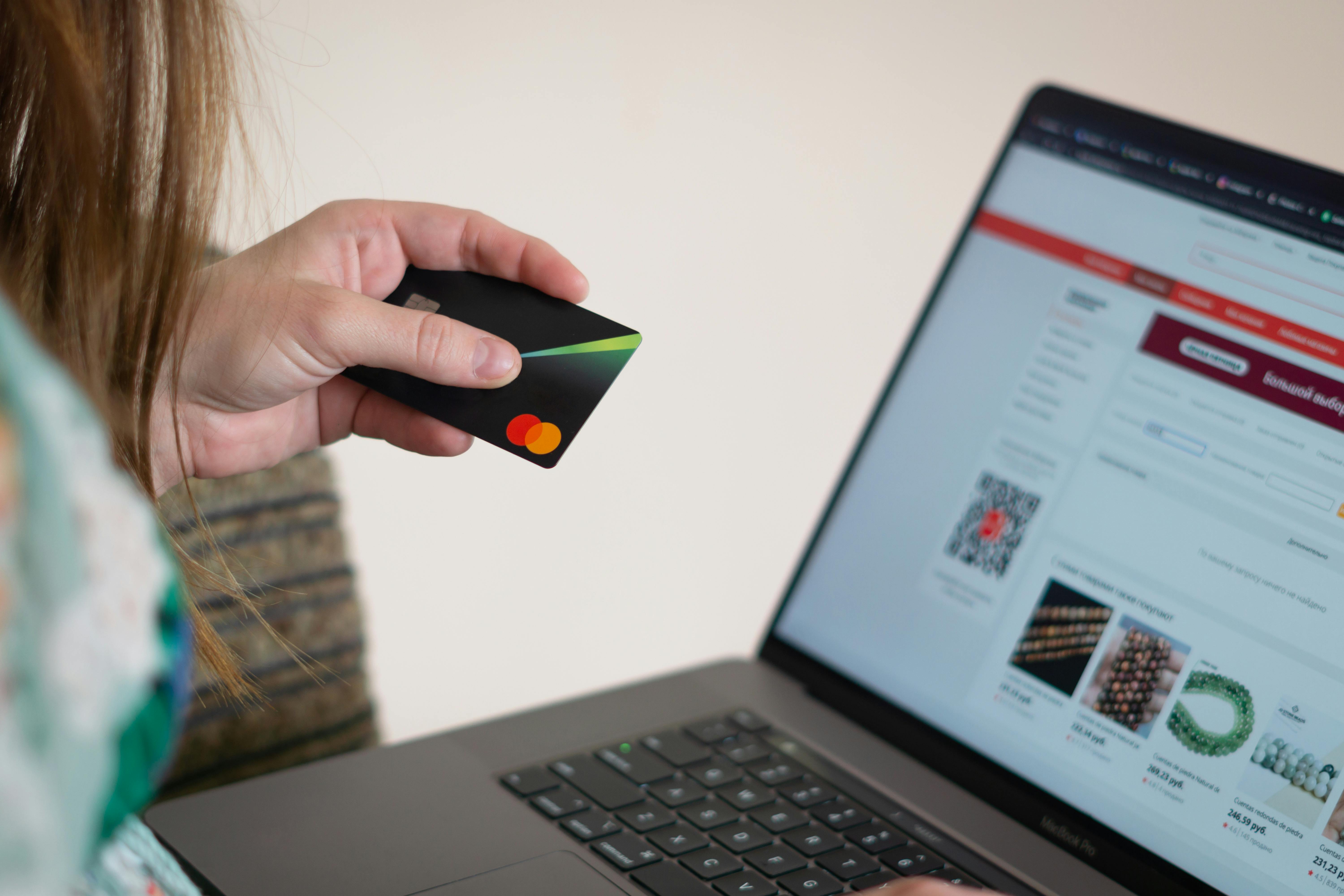 Person holding a bank card while making an online payment on a laptop