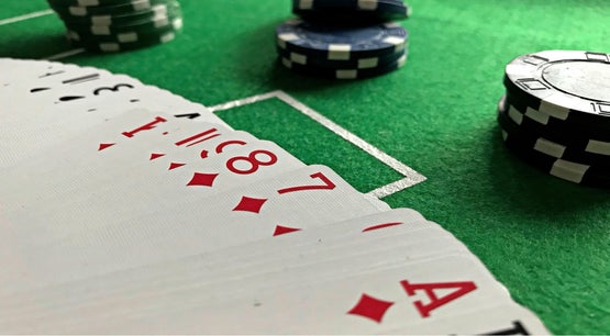  Close-up of playing cards and poker chips on a green casino table