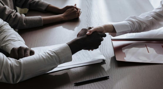 Business handshake between two people during a partnership meeting at an office desk